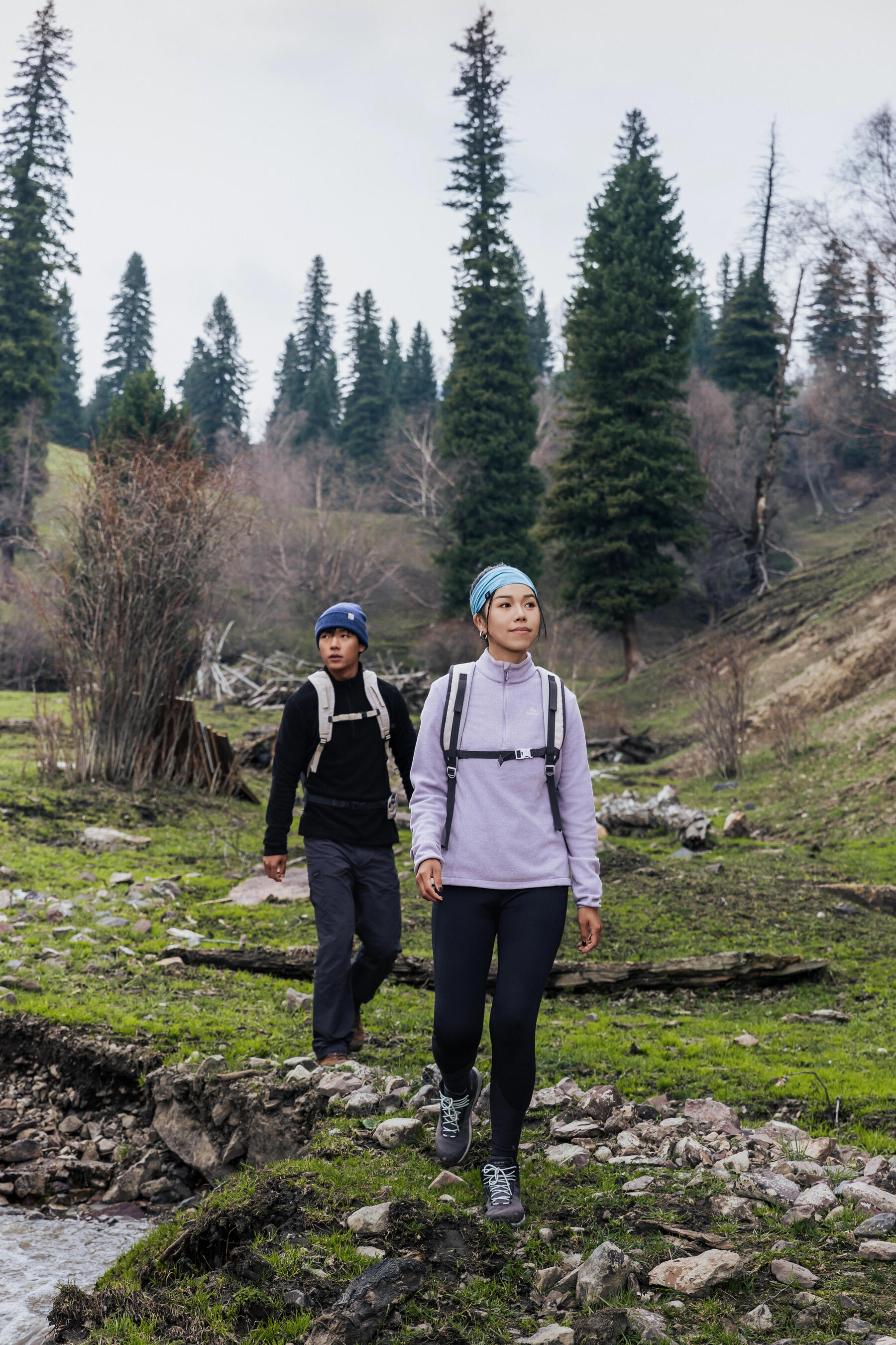 Para wędrująca z plecakami i w butach trekkingowych po dolinie w górach