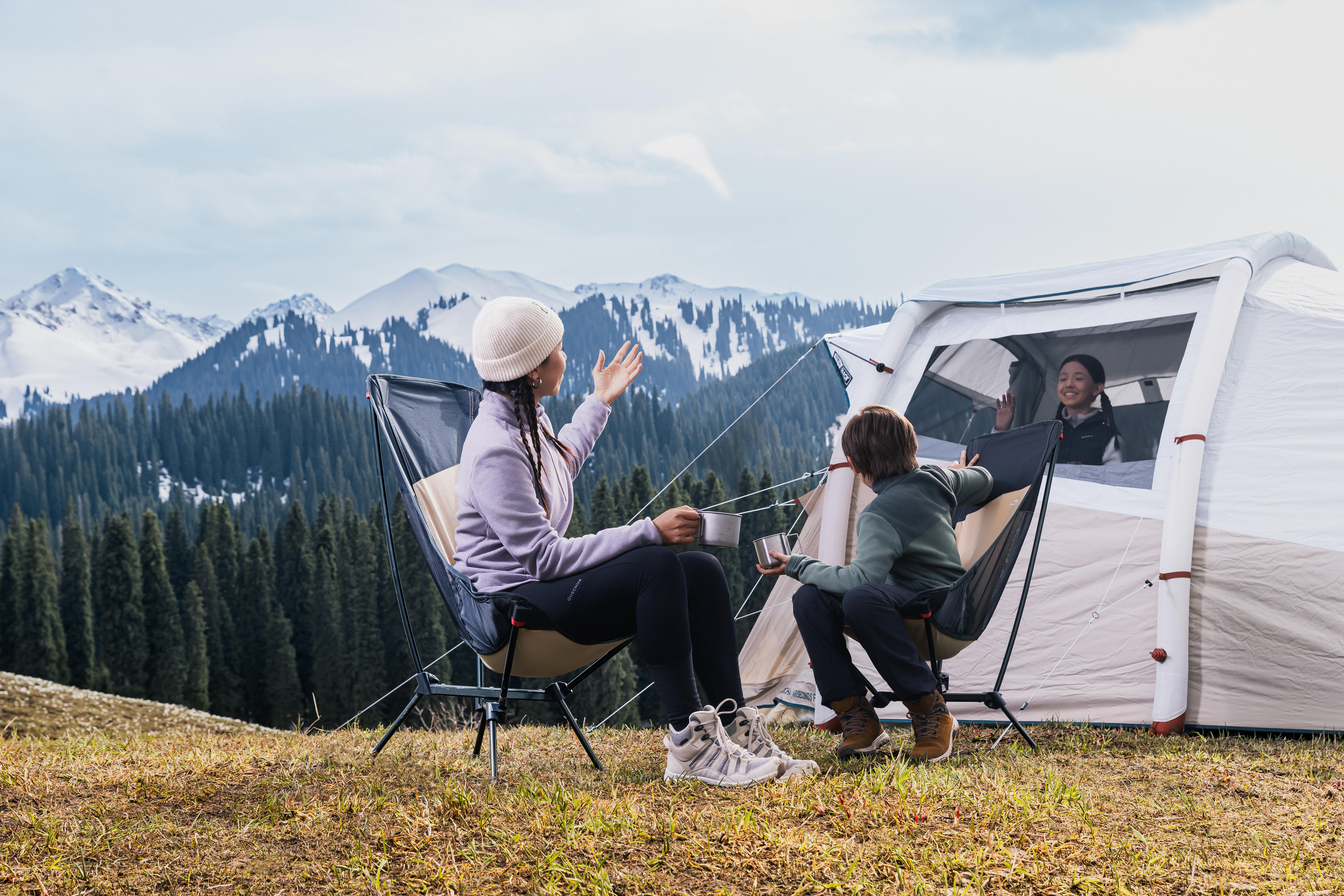 Family relaxing outside an inflatable camping tent in the mountains