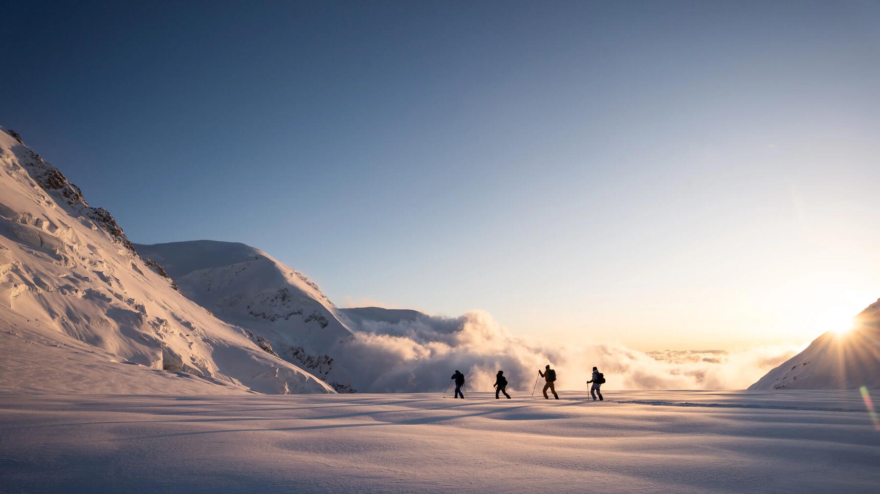 Skifahrer laufen mit Stöcken in der Sonne