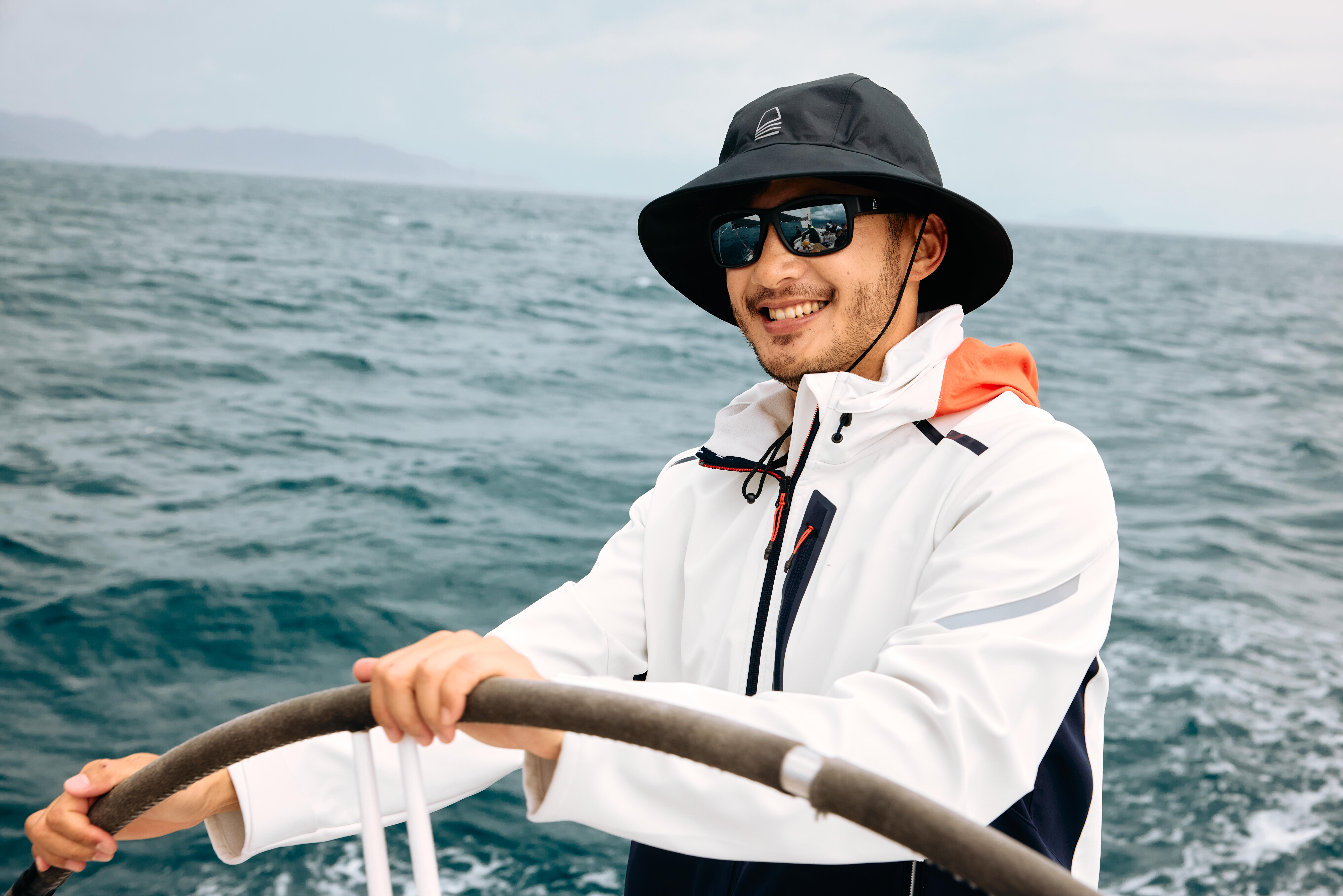 Angler wearing a fishing hat while steering a boat at sea