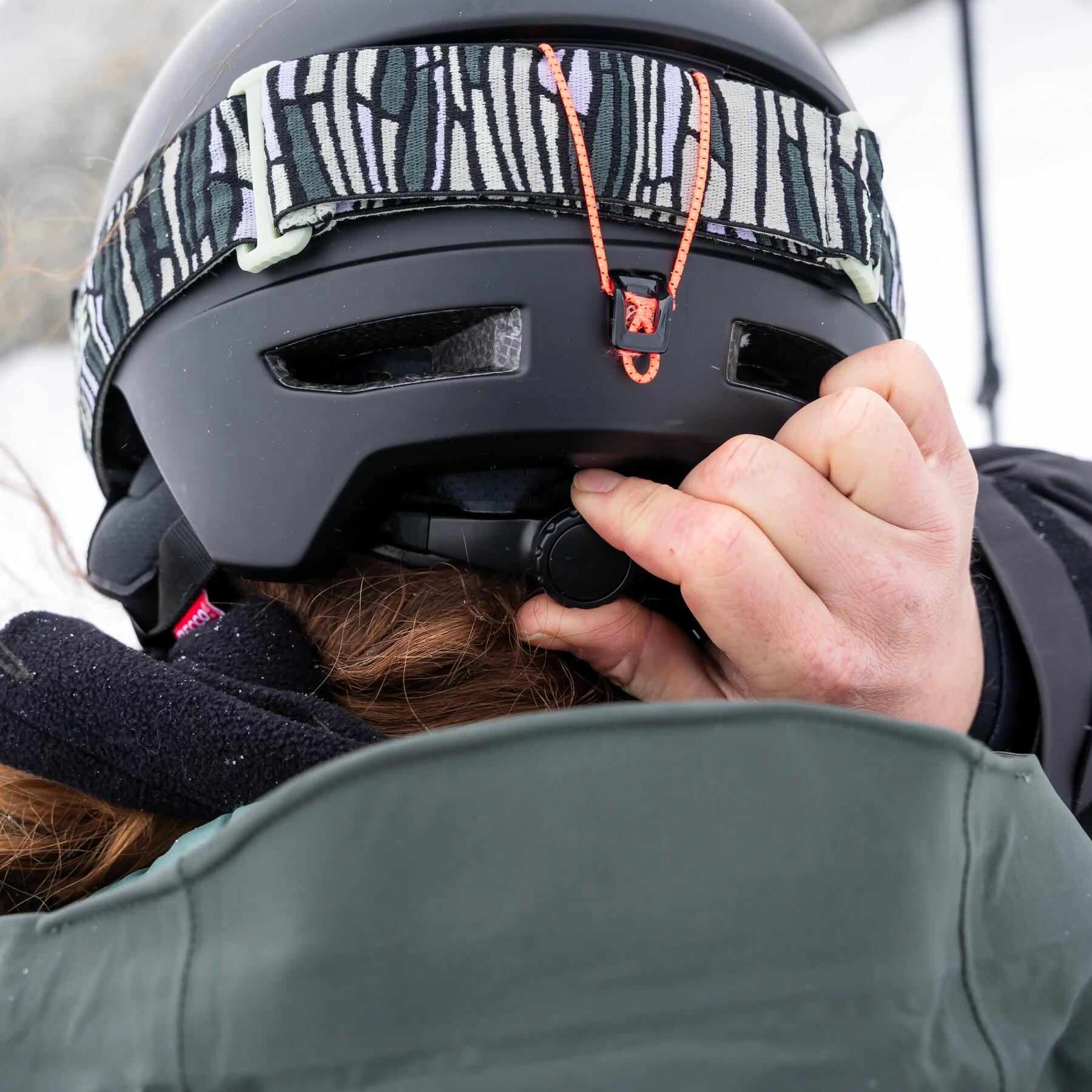 Homme au ski en train de régler son casque de ski bleu decathlon avec la technologie mips