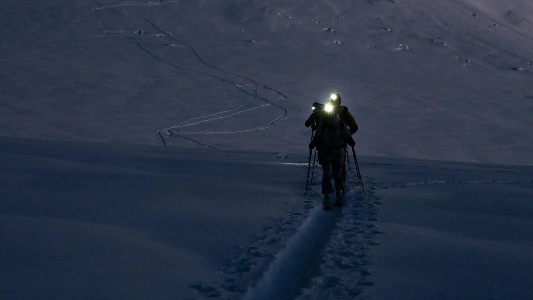Gruppe von Tourenskiern in der Dunkelheit durch die Alpen unterwegs
