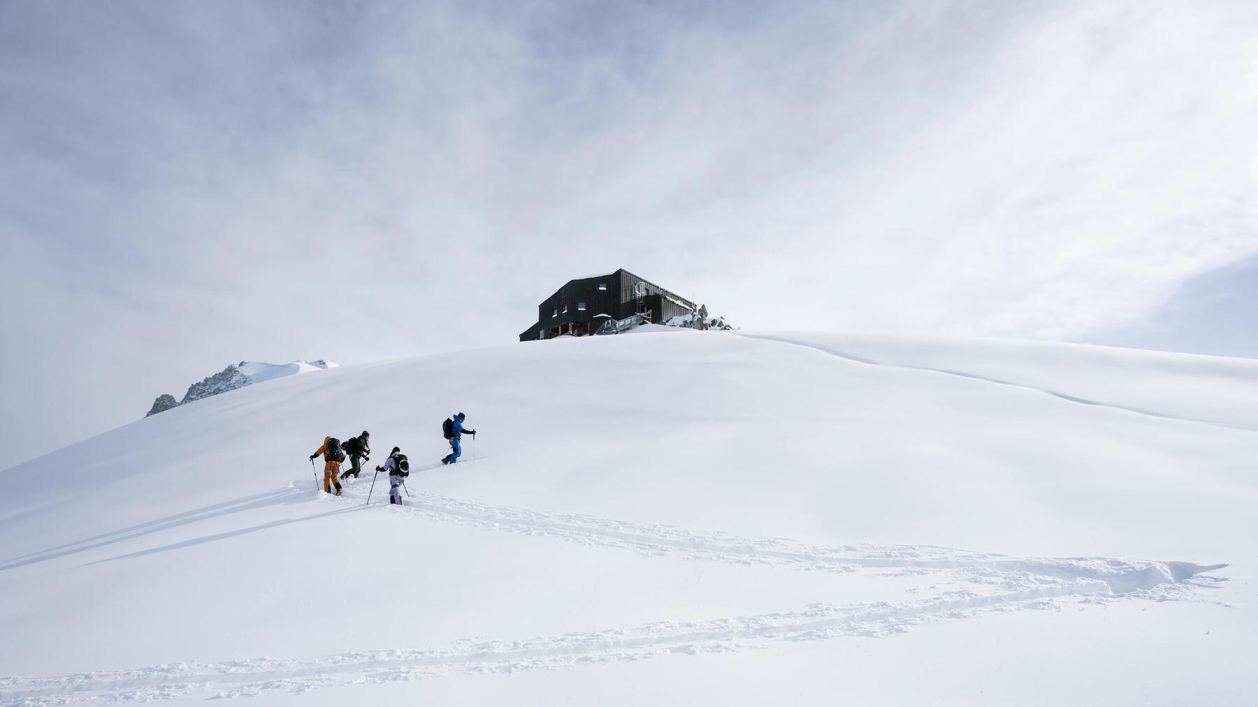 Vier Skitourengeher beim Aufstieg an einem verschneiten Hang in den Alpen