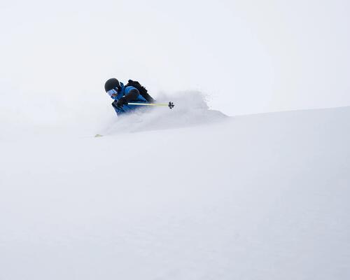 Mężczyzna szusujący na specjalnych nartach on piste na stoku