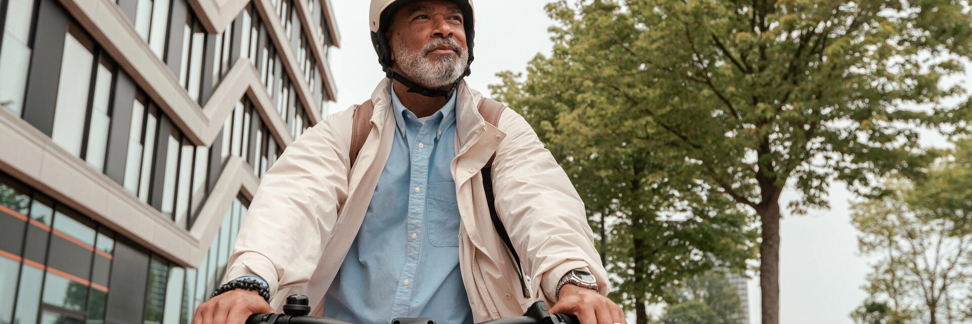 Senior w kasku rowerowym jadący na rowerze elektrycznym