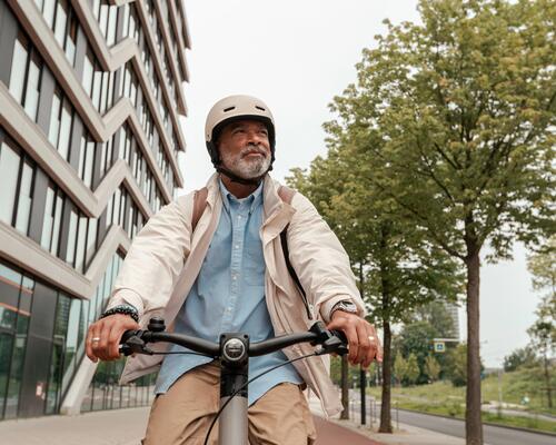 Senior w kasku rowerowym jadący na rowerze elektrycznym 