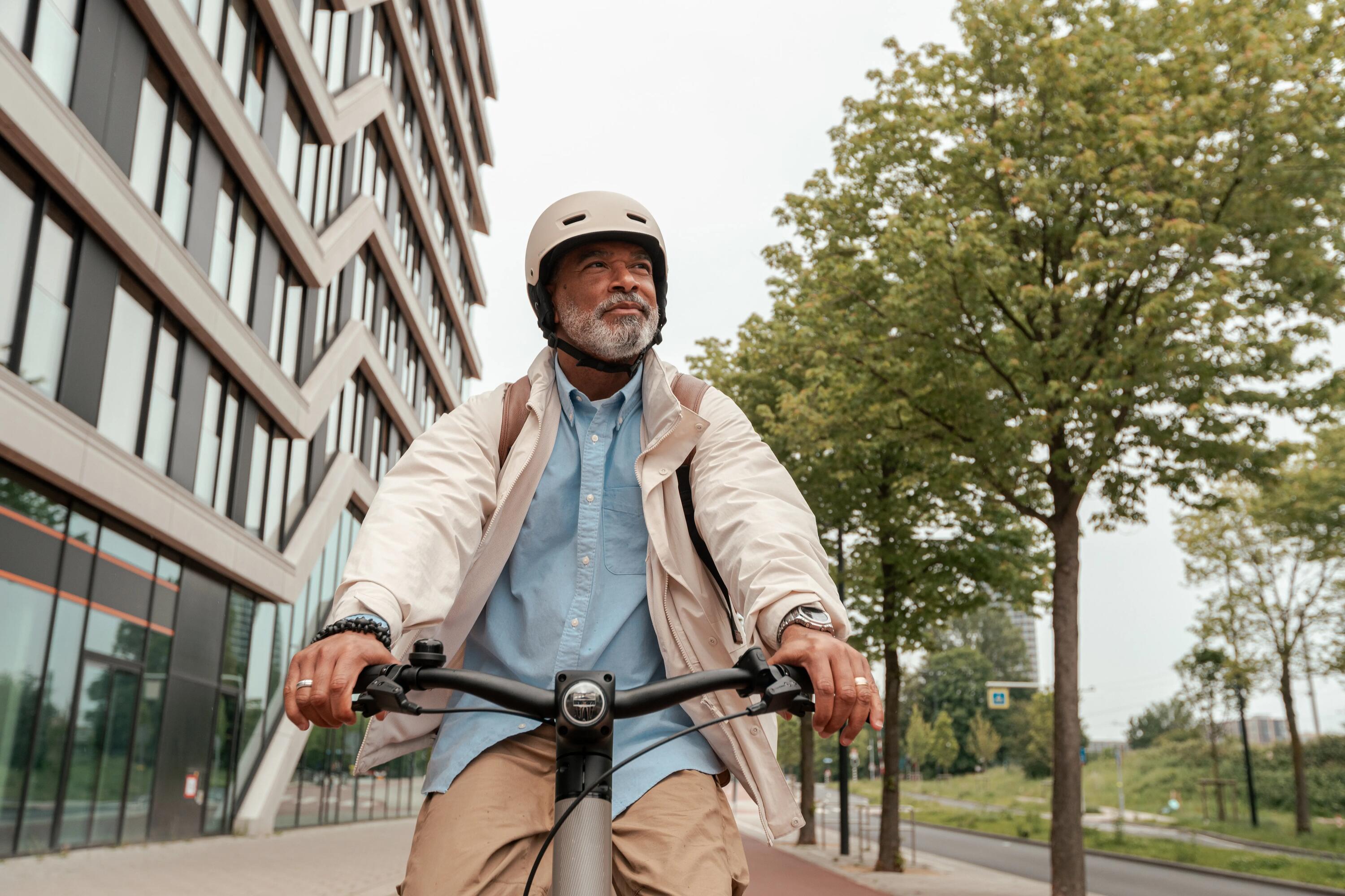 Senior w kasku rowerowym jadący na rowerze elektrycznym