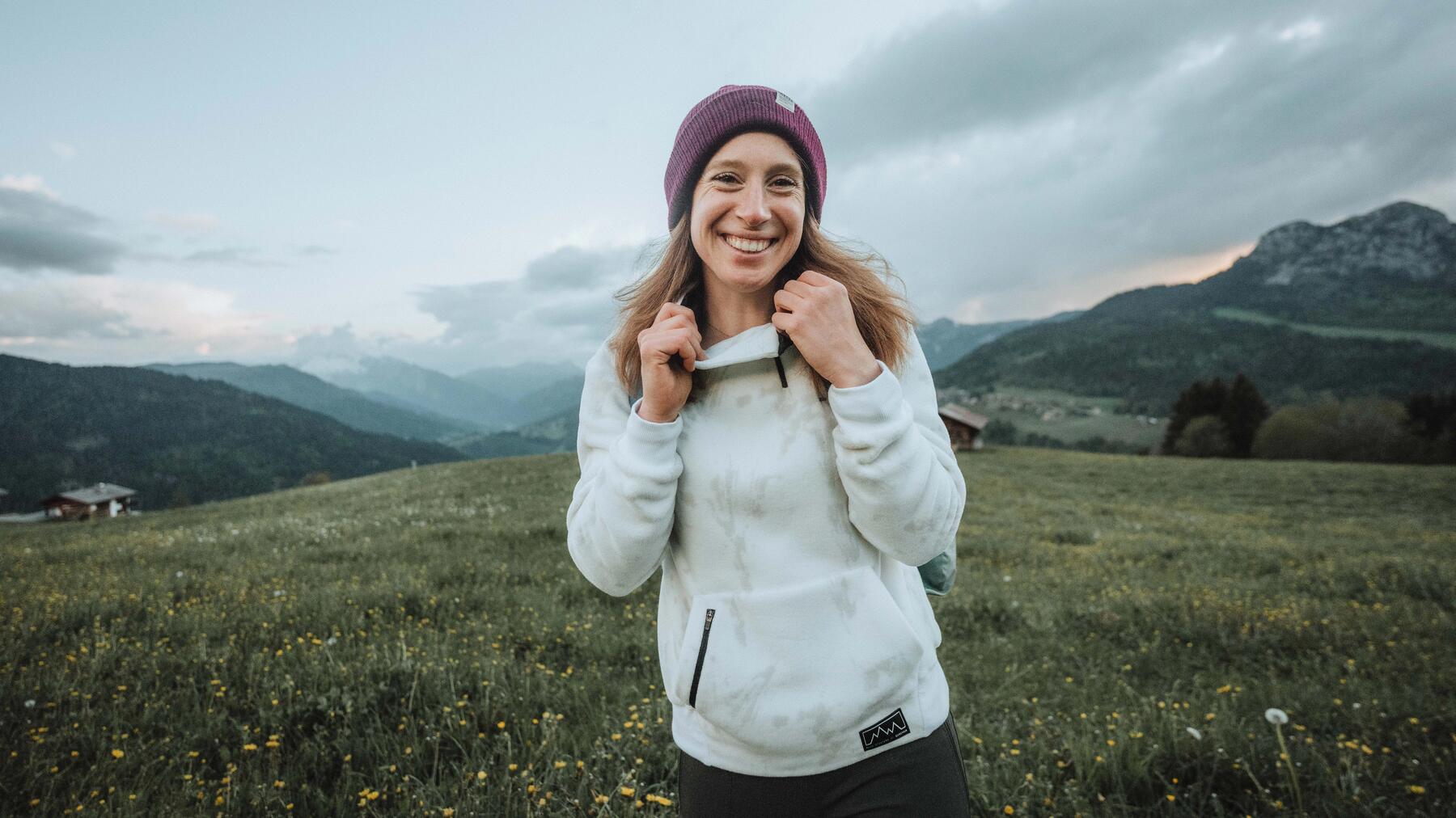 Frau vor Naturkulisse in Wanderbekleidung.