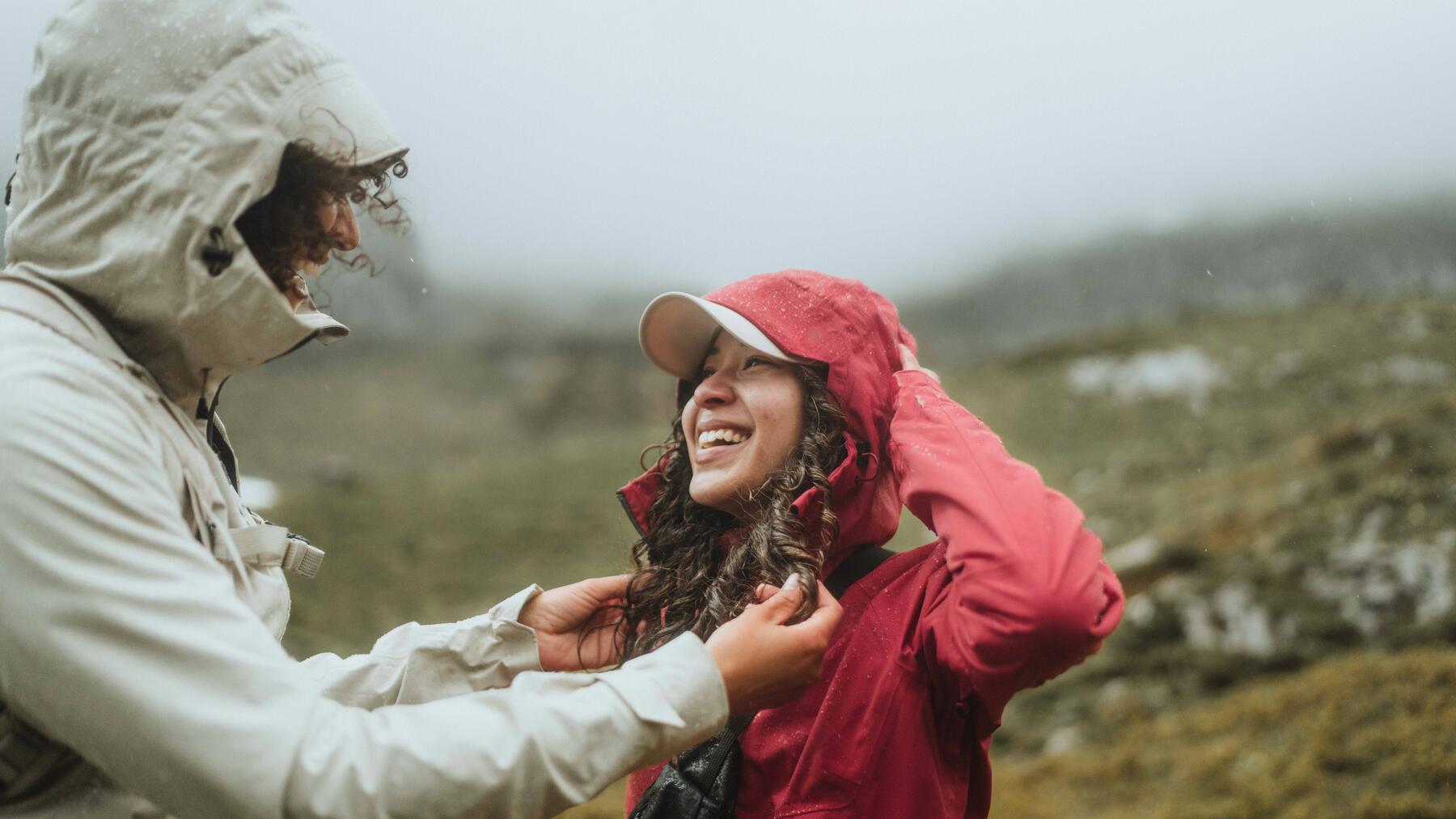 Zwei Frauen tragen Regenjacken und gehen im Regen spazieren