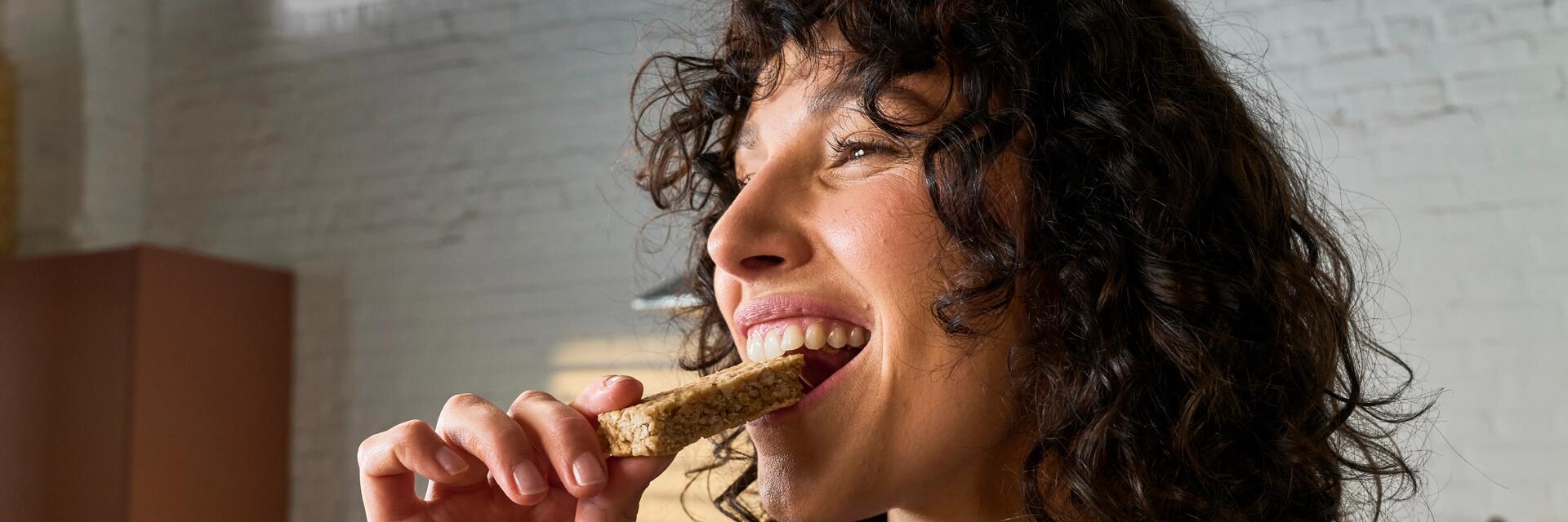 Frau isst einen gesunden Riegel als Snack für zwischendruch