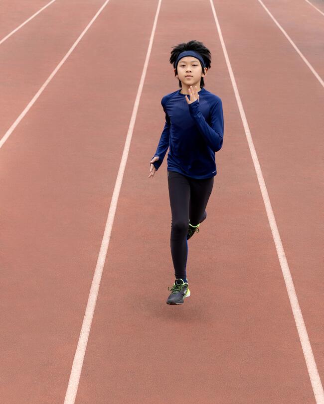 Junge läuft auf roter Laufbahn, trägt blaues Oberteil und schwarze Leggings, kontrastierende Linien, dynamische Bewegung.