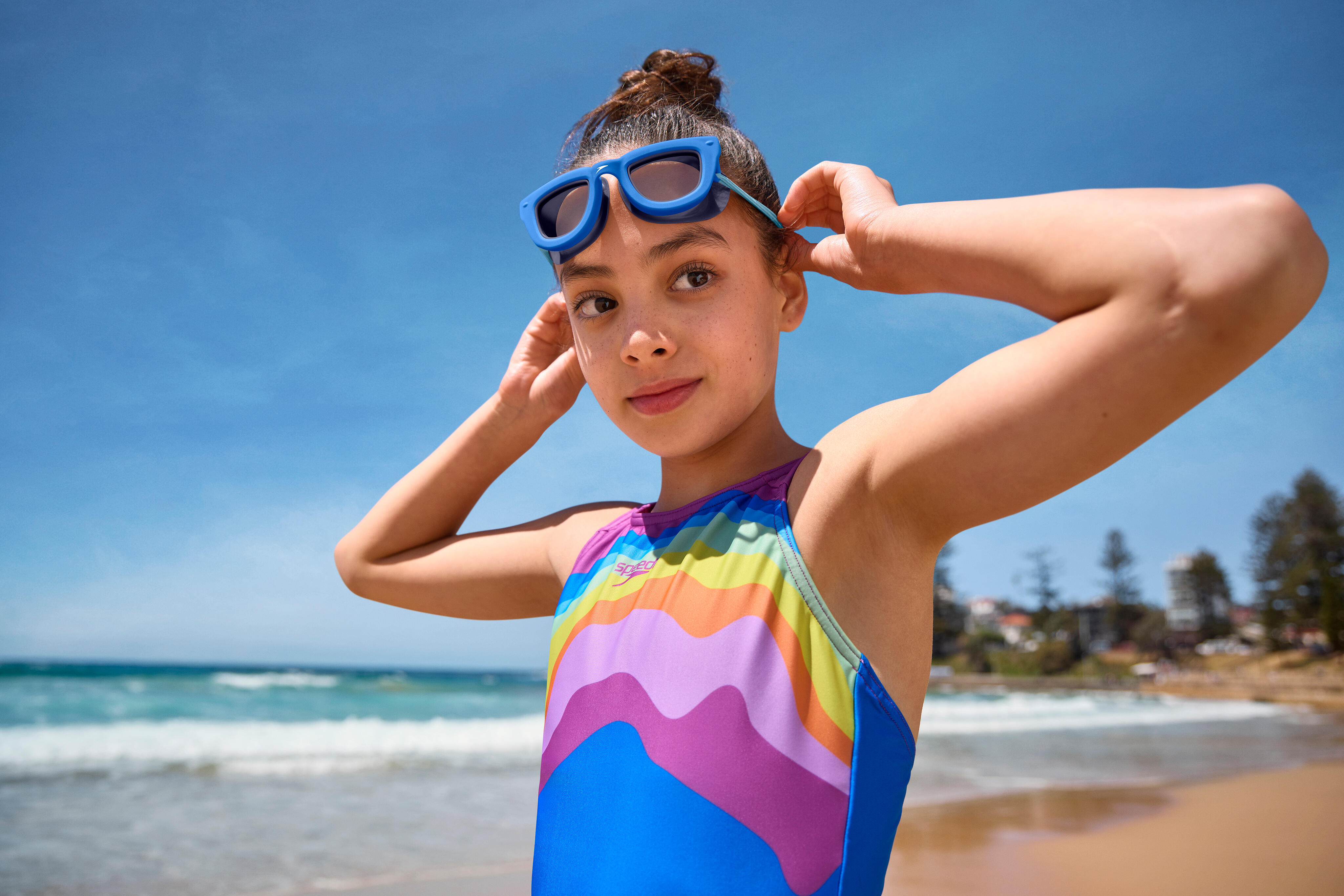 Child adjusting kids swimming goggles before a swim at the beach.