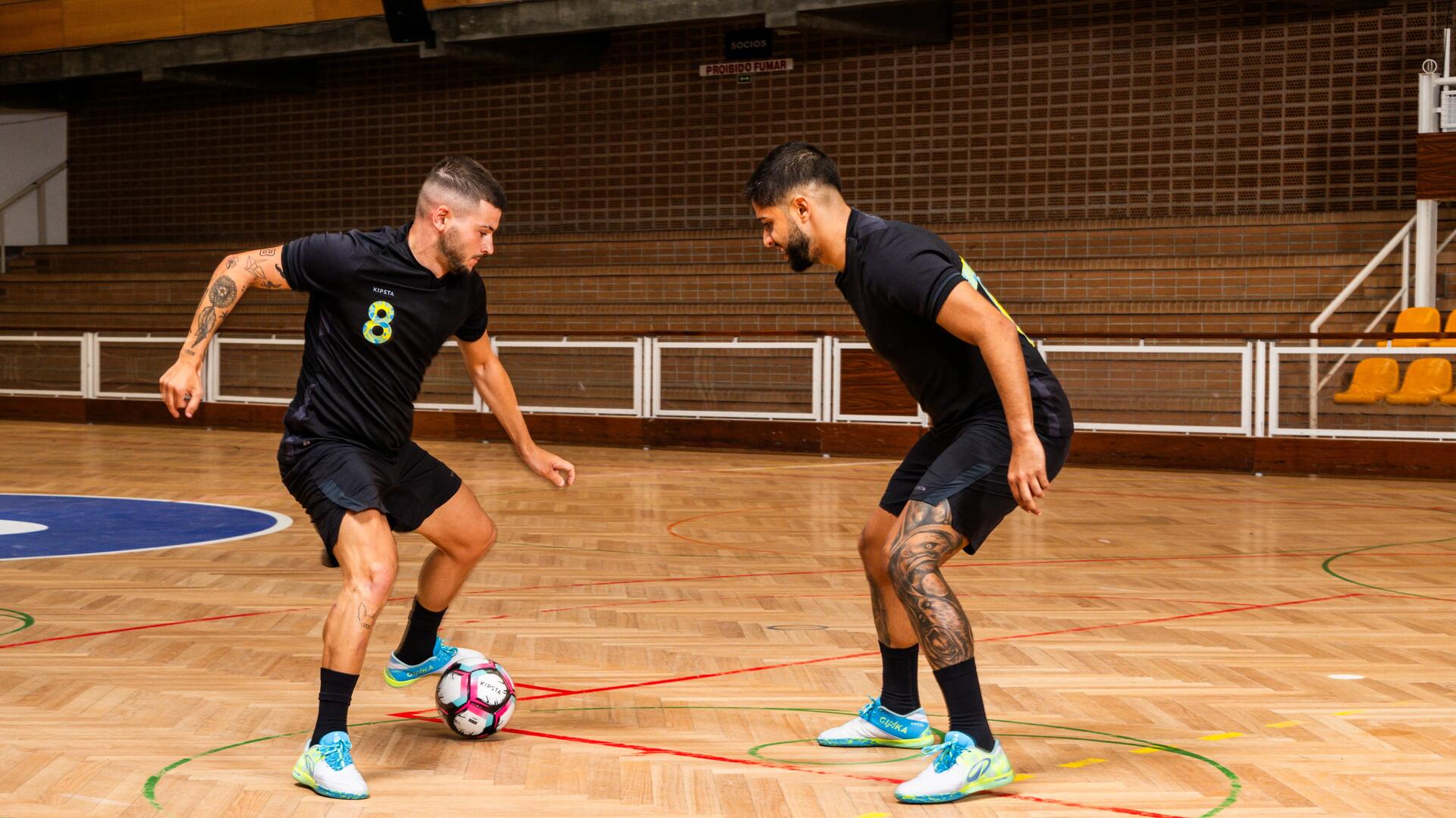 Zwei Männer in schwarzem Outfit beim Futsal gegeneinander.