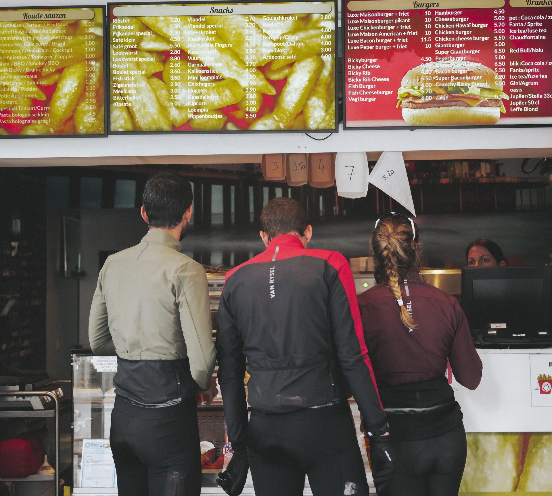 Three cyclists ordering food at a chicken shop