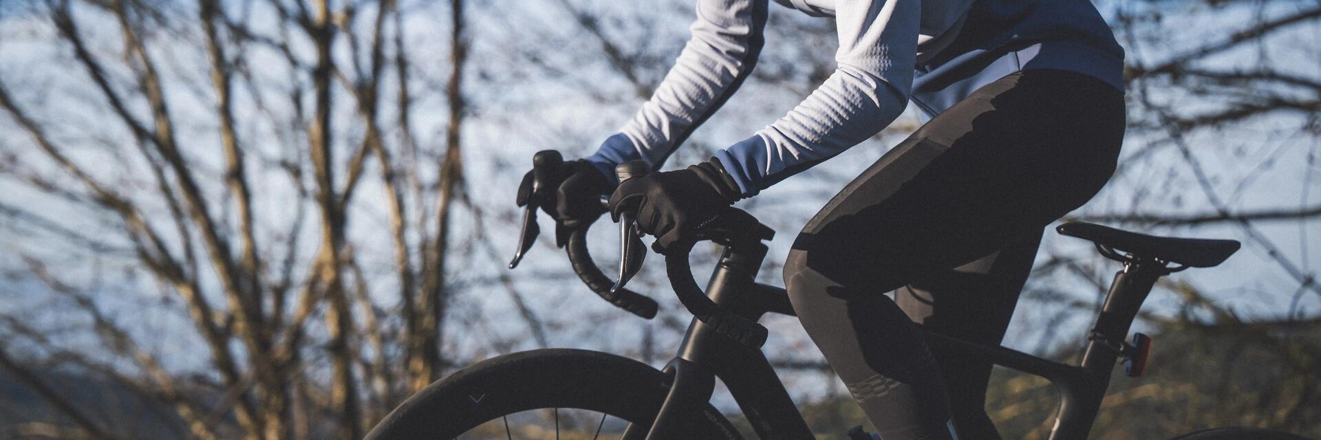 Kobieta w kasku i w okularach jadąca w rękawiczkach na rowerze