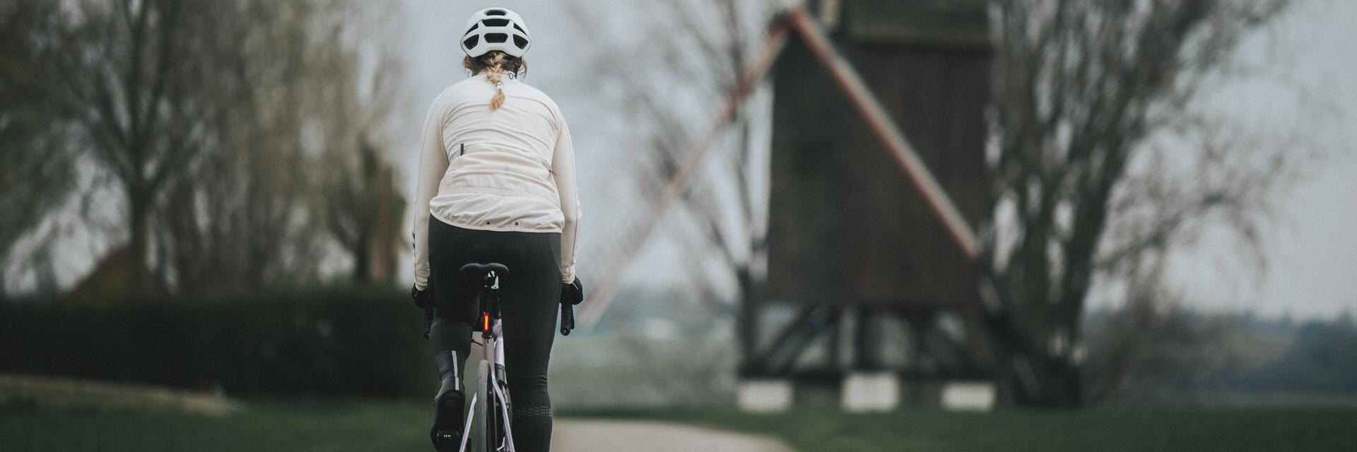 Kobieta w kasku rowerowym jadąca na rowerze z prawidłowo ustawionym siodełkiem