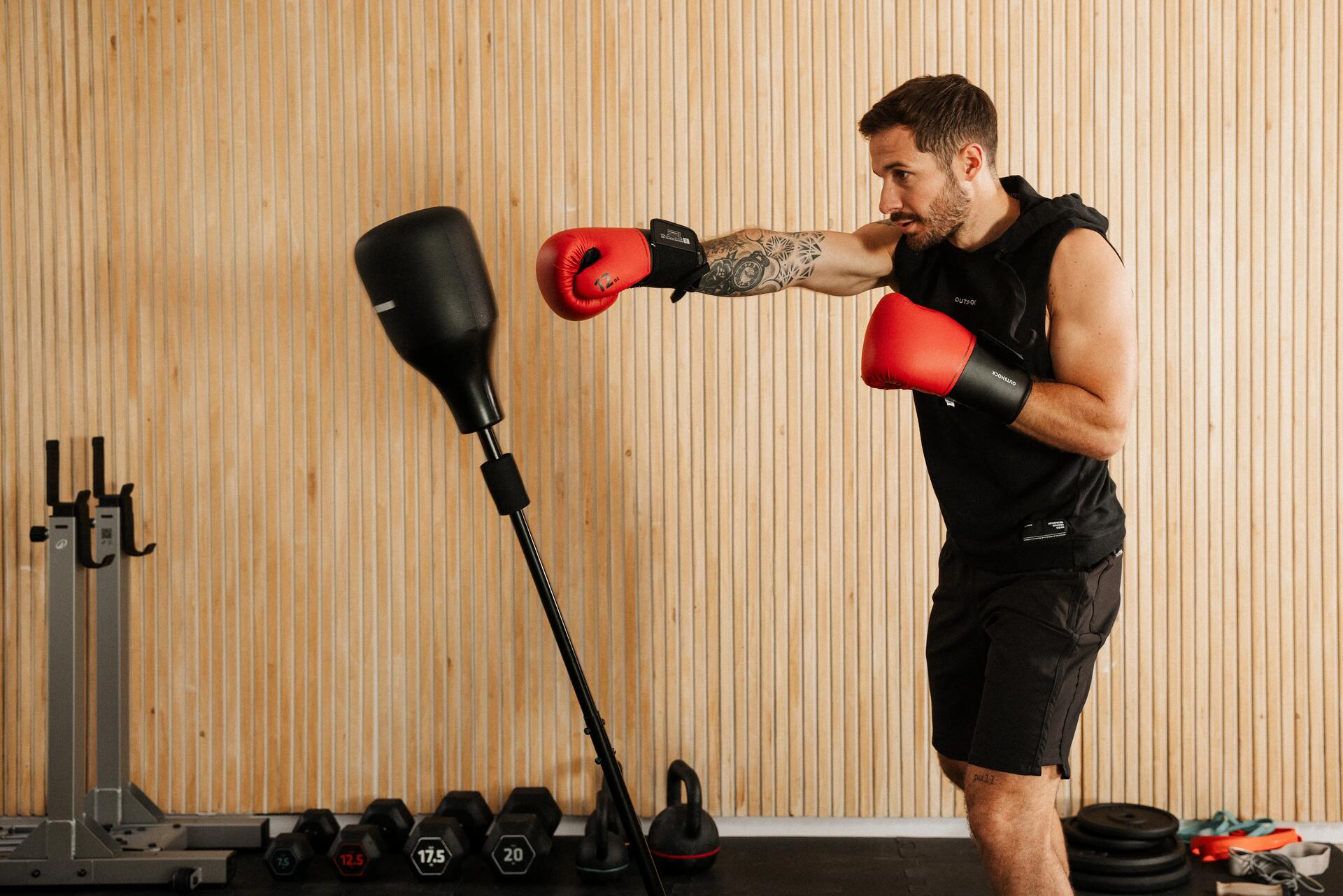 Ein Mann mit Boxhandschuhen schlägt im Heimfitnessstudio gegen einen freistehenden Reflex-Boxsack.