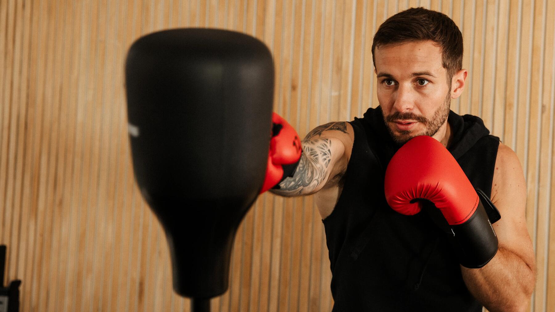 Mann boxt gegen einen Boxsack mit Boxhandschuhen