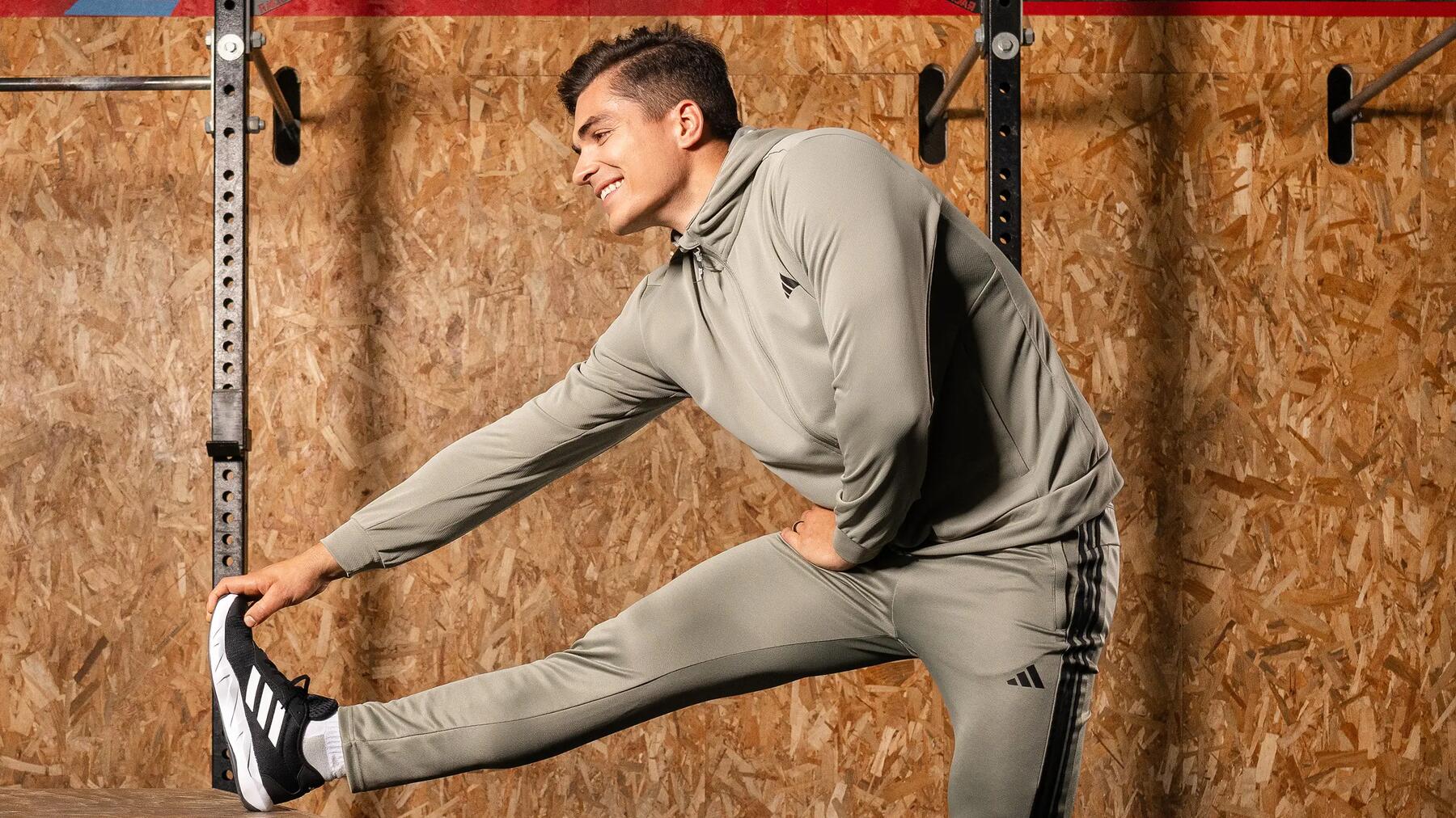 Ein Mann in Sportoutfit macht drinnen dynamisches Dehnen