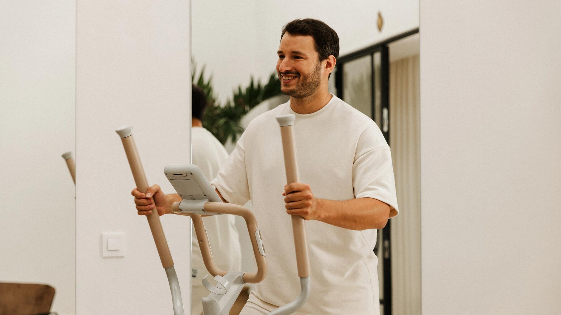Ein Mann trainiert auf dem Crosstrainer im Wohnzimmer