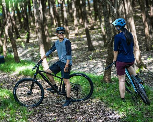 Mężczyzna i kobieta w kaskach rowerowych odpoczywający podczas jazdy na rowerze w lesie