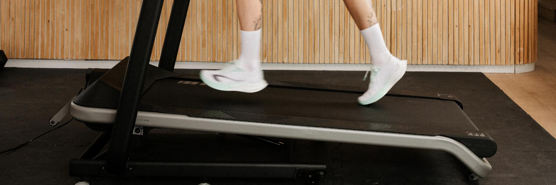 Nahaufnahme von Beinen in Laufschuhen auf einem Laufband im Zimmer