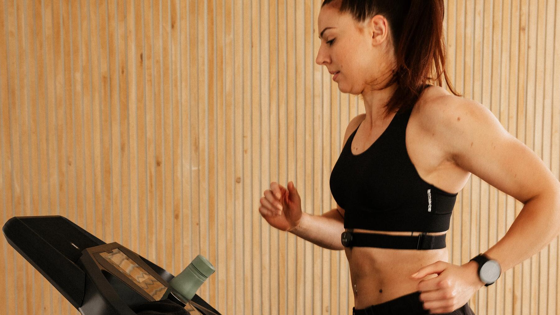 vrouw die op een loopband loopt met hartslagmeter