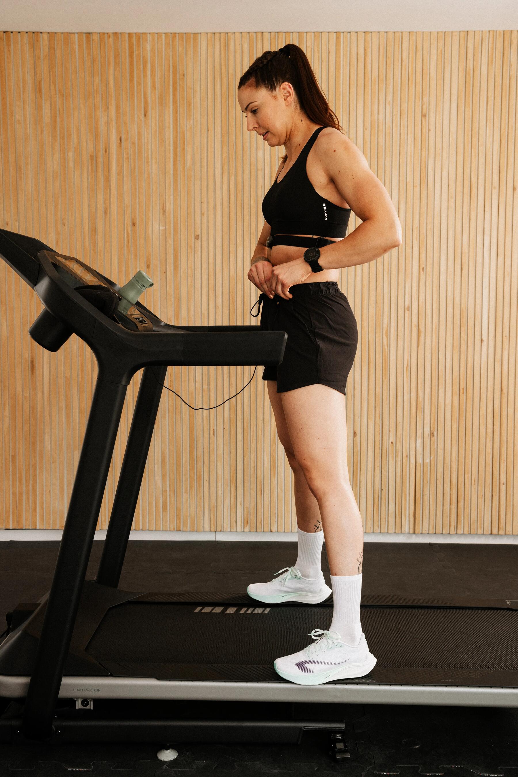 Frau steht auf dem Laufband und startet ihr Training für Anfänger