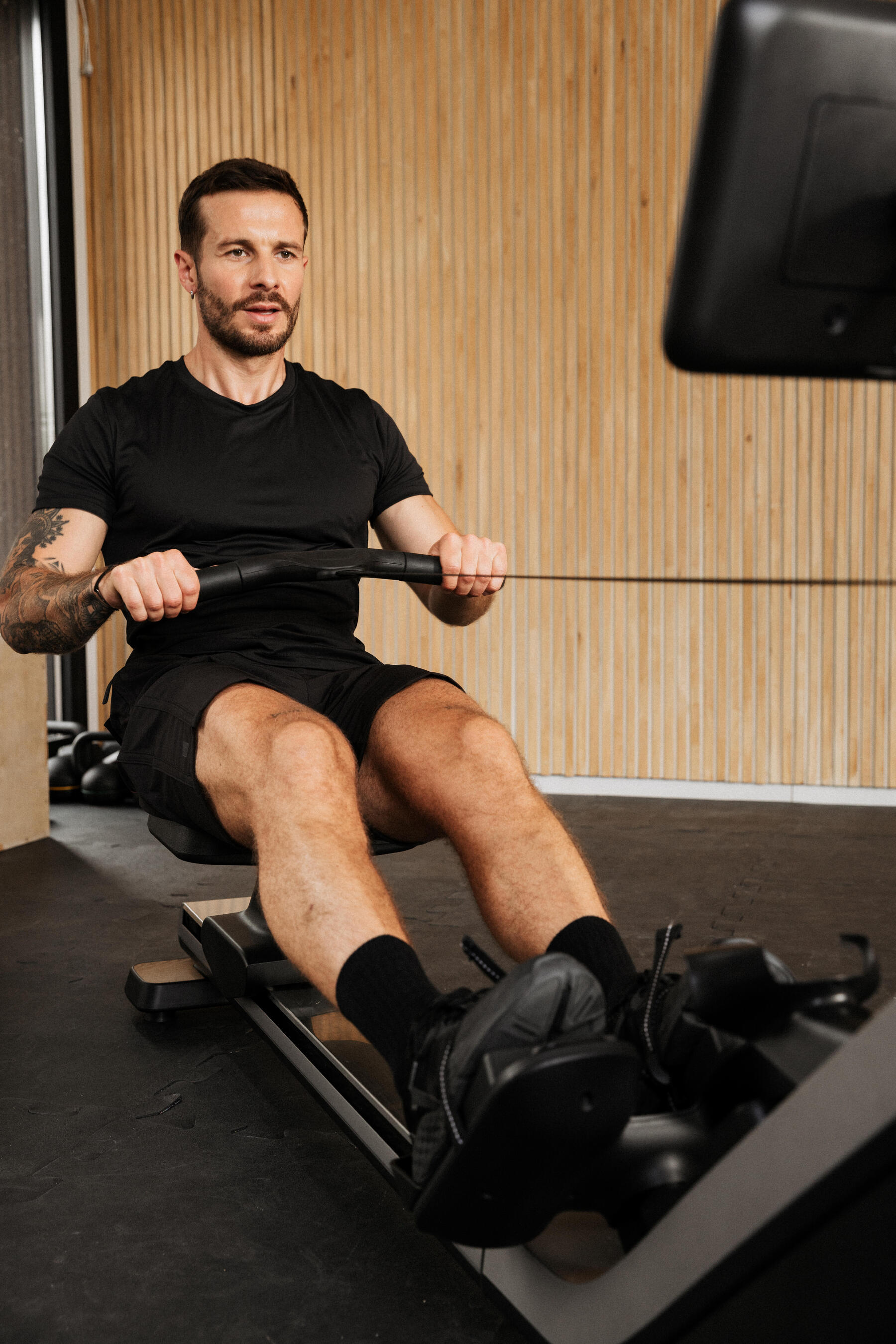 Mann nutzt einen Trainingplan auf einem Rudergerät