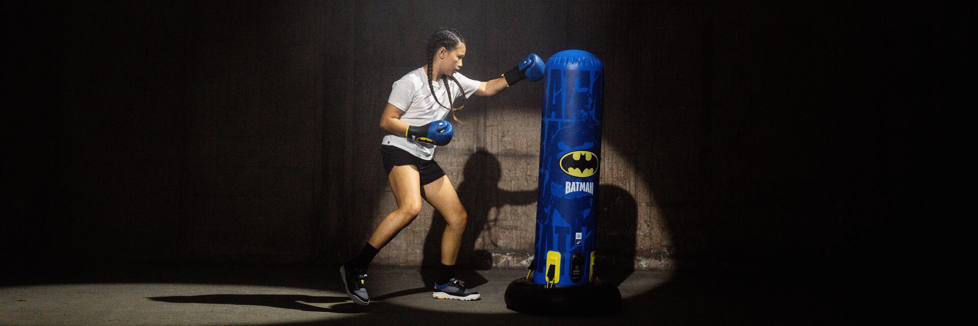 Dziewczyna trenująca cardio boxing uderzając w rękawicach w worek treningowy