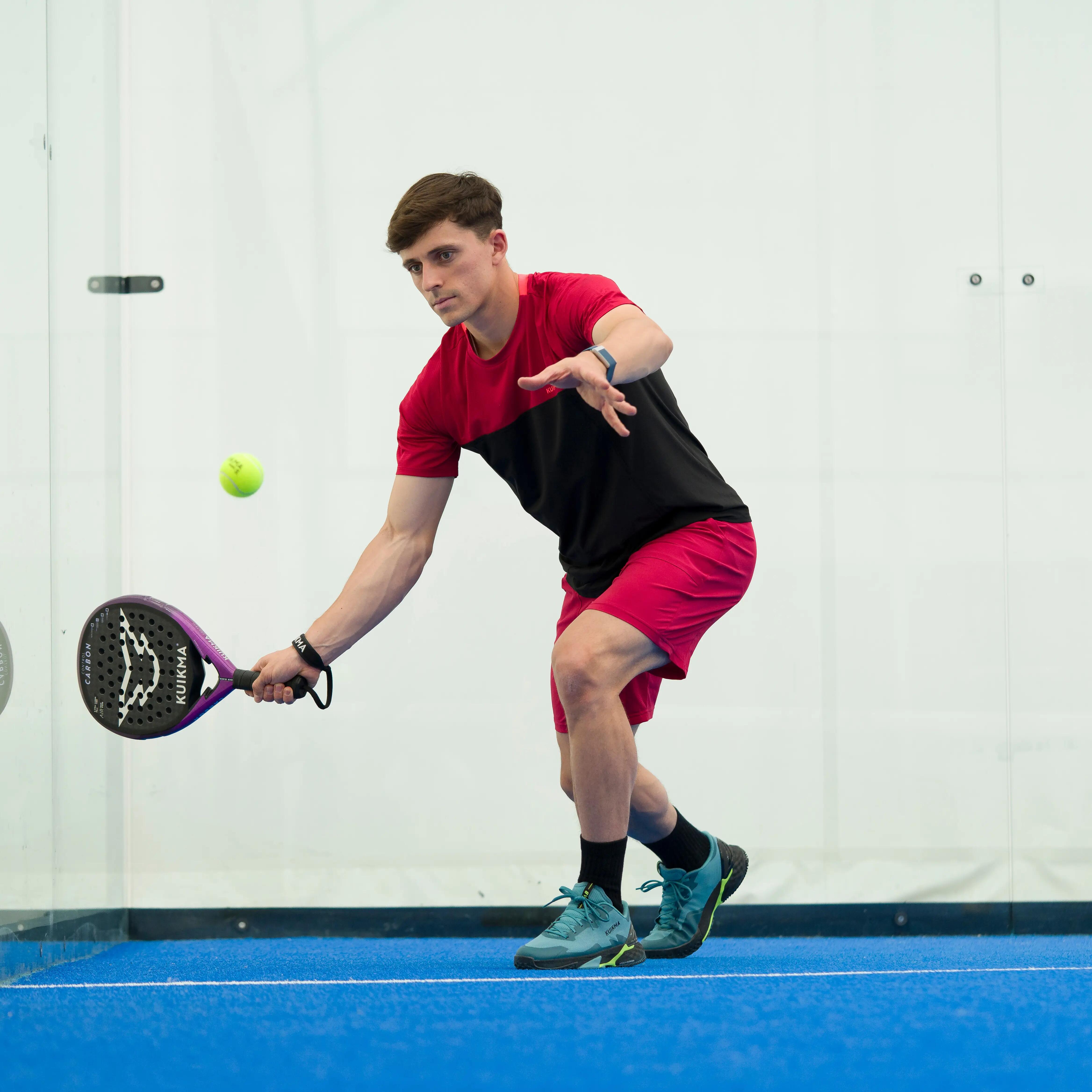 Mladenič igra padel na zaprtem igrišču, v trenutku, ko udarec leti proti žogi, ki prihaja proti njemu.