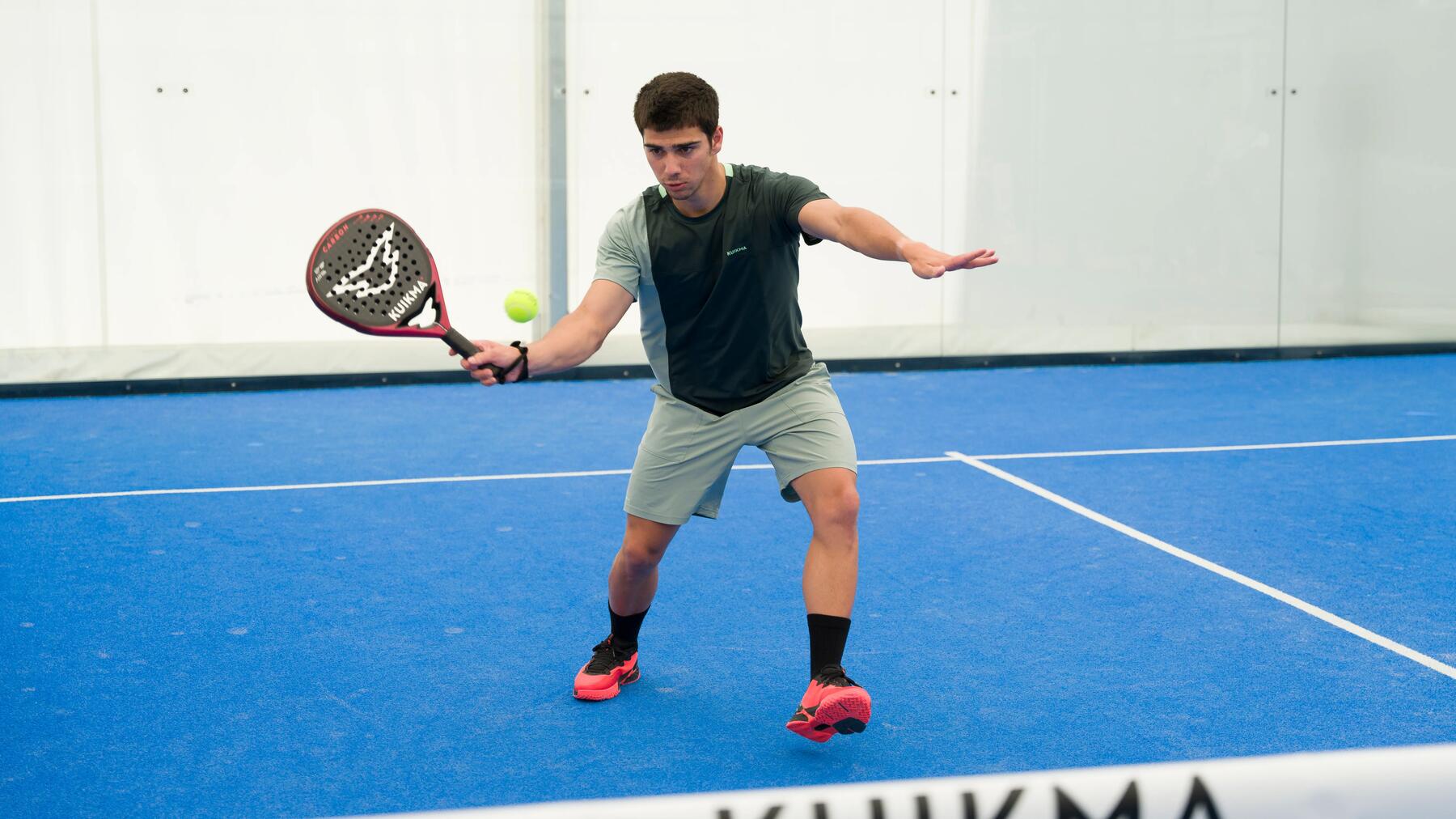 Ein Padelspieler ist auf einem Padelcourt aktiv und holt mit ihrem Schläger zum Schlagen des Balles aus