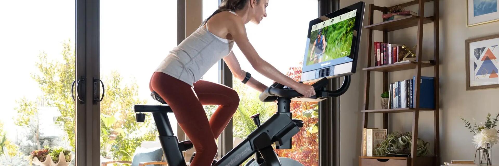 Kobieta w odzieży sportowej ćwicząca na rowerze stacjonarnym w domu
