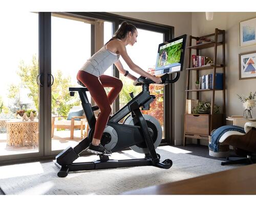 Kobieta w odzieży sportowej ćwicząca na rowerze stacjonarnym w domu