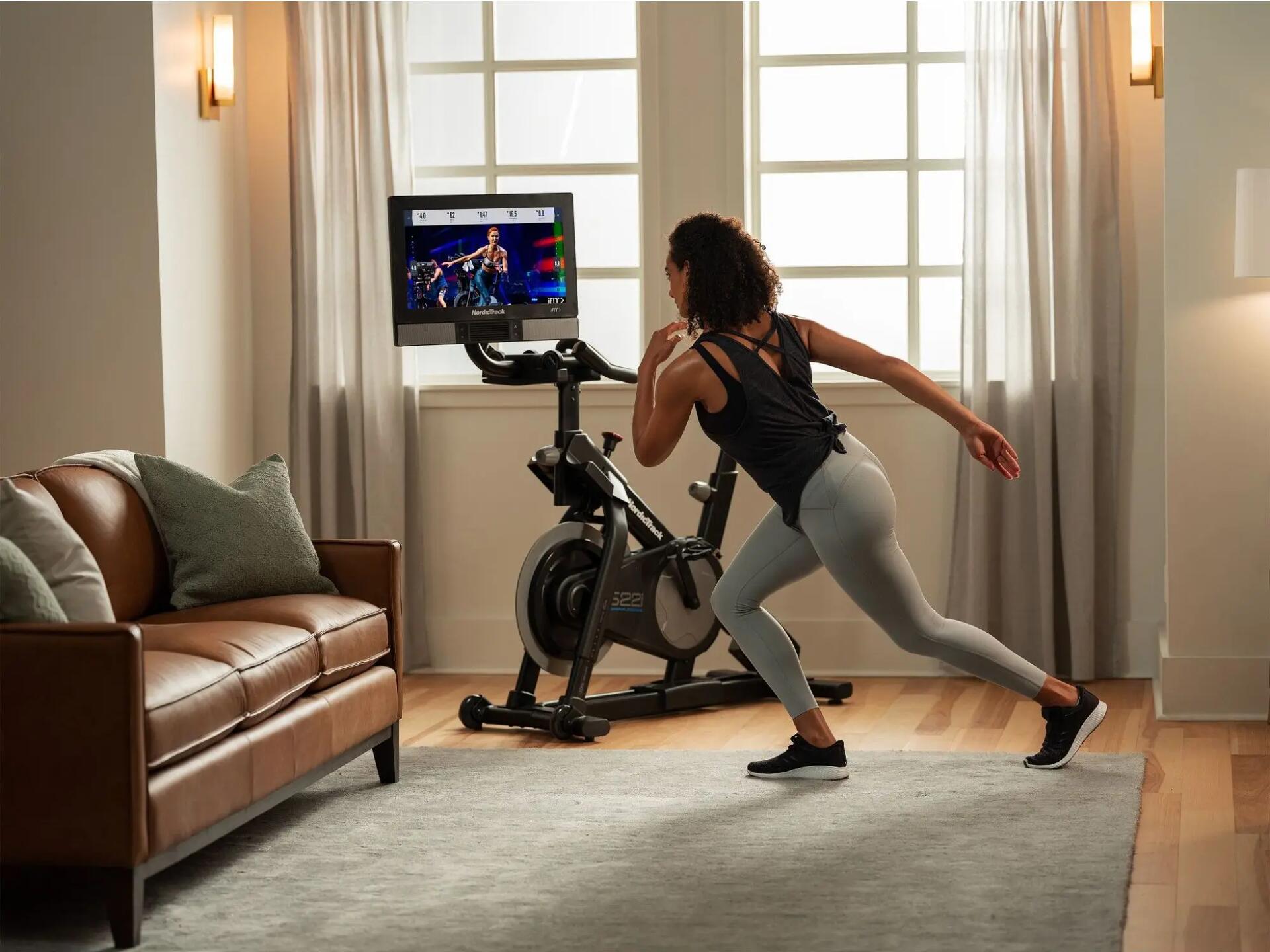 Kobieta w stroju sportowym trenująca cardio z aplikacją na monitorze rowerka stacjonarnego