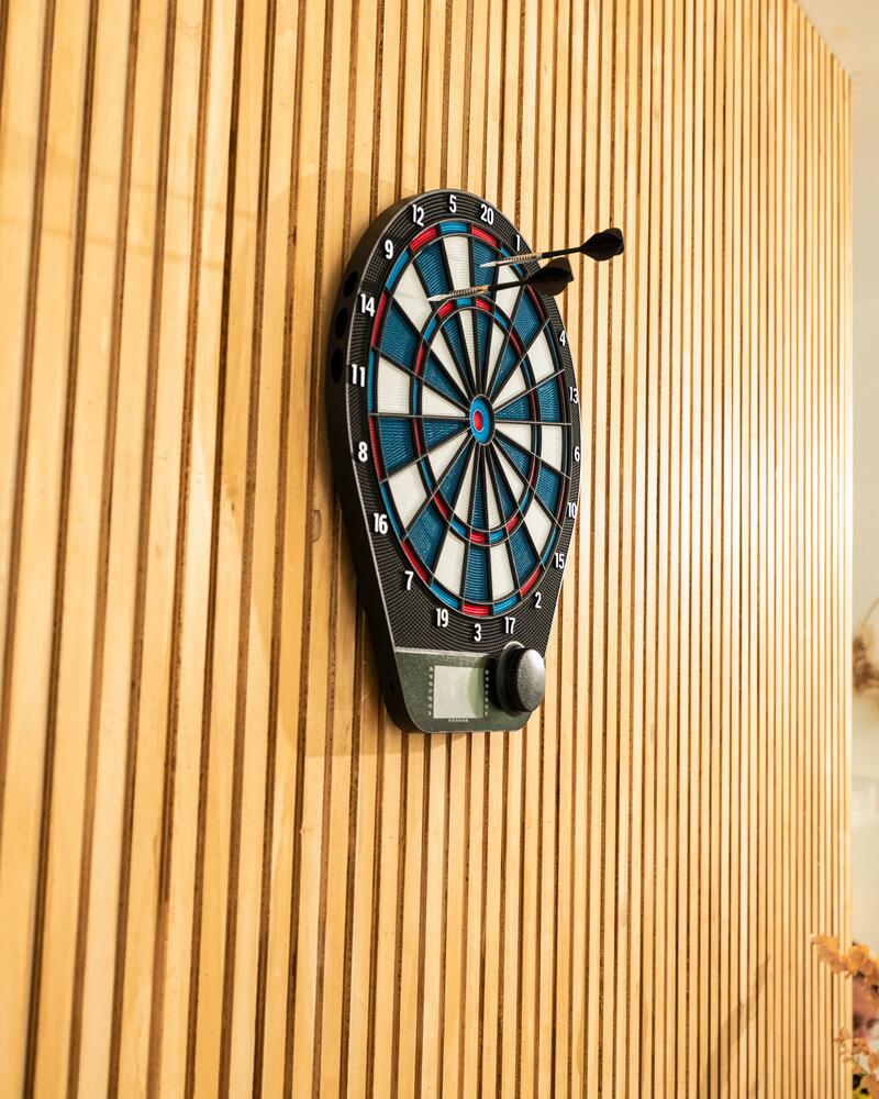 Eine elektrische Dartscheibe, die an einer Holzwand hängt und in der 2 Soft-Darts stecken.