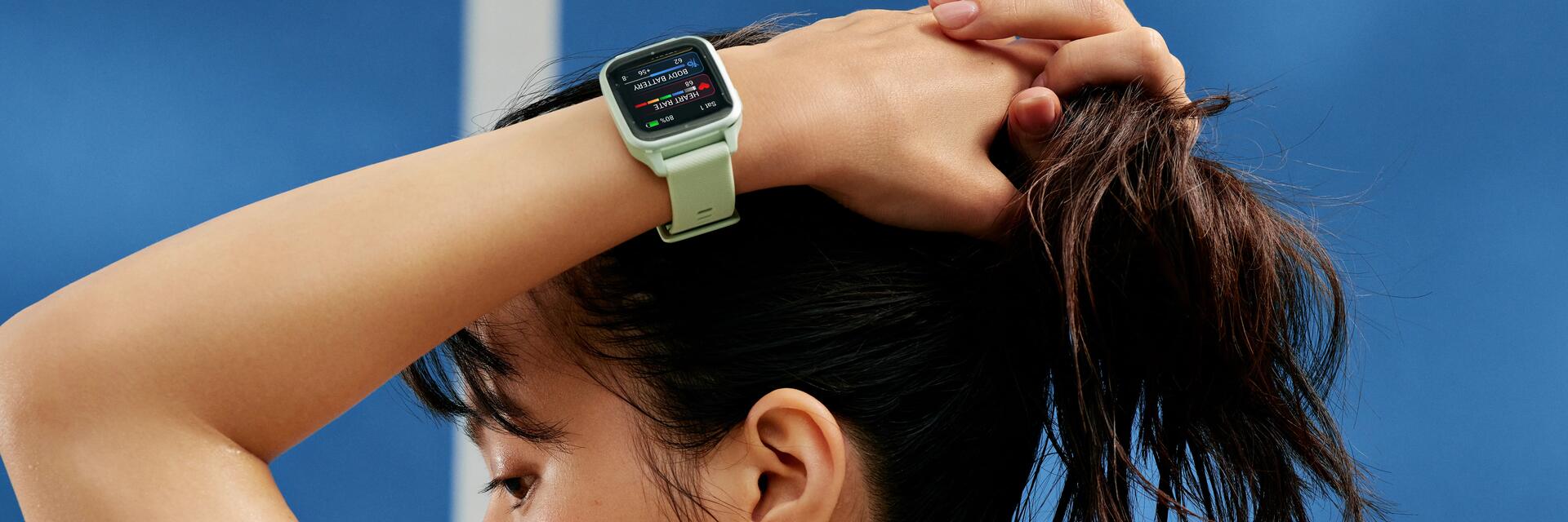 Kobieta z założonymi rękami na głowie na jednym ręku smartwatch