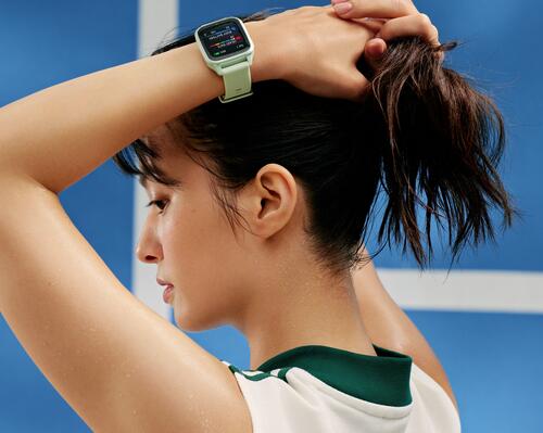 Kobieta z założonymi rękami na głowie na jednym ręku smartwatch