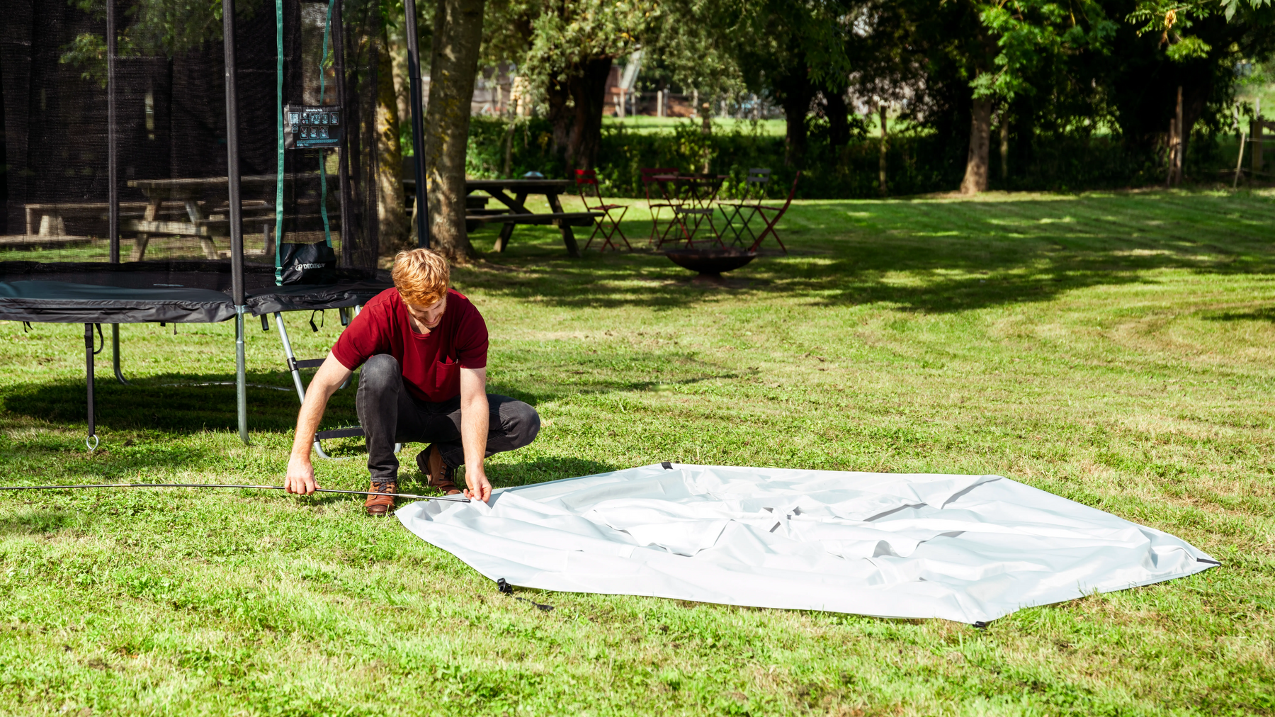 Ein Mann baut im Garten ein Trampolin auf