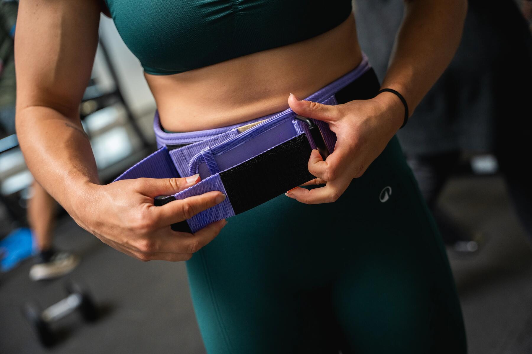 Kobieta w legginasach i staniku sportowym zapinająca pas do treningu crossfit