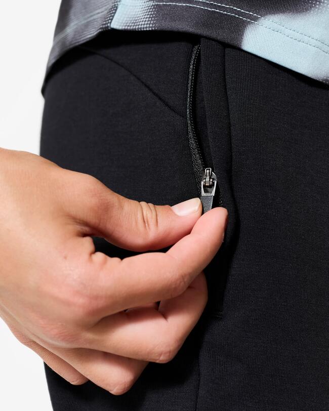 Junge zeigt seitlichen Reißverschluss an der Tasche der Jogginghose.