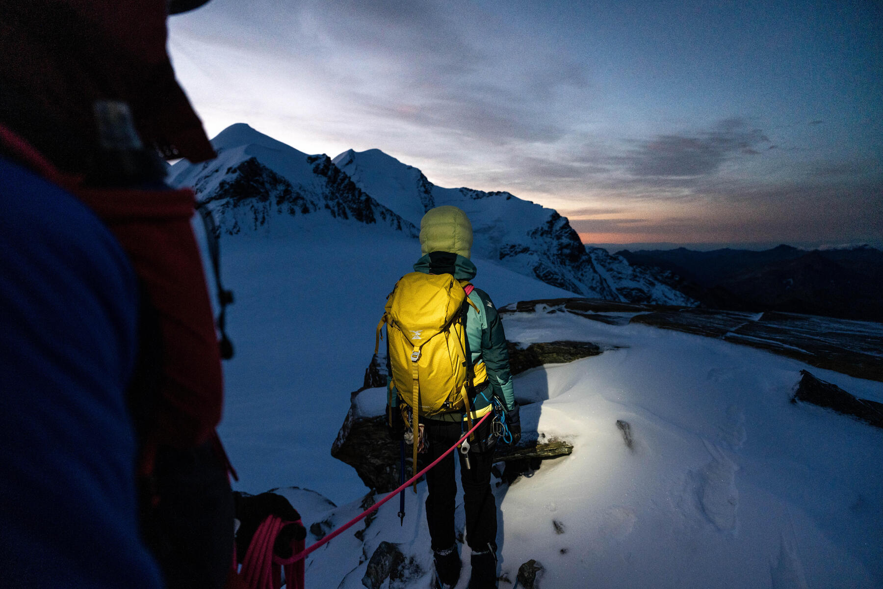 Alpiniści idący po śniegu przypięci do siebie linką