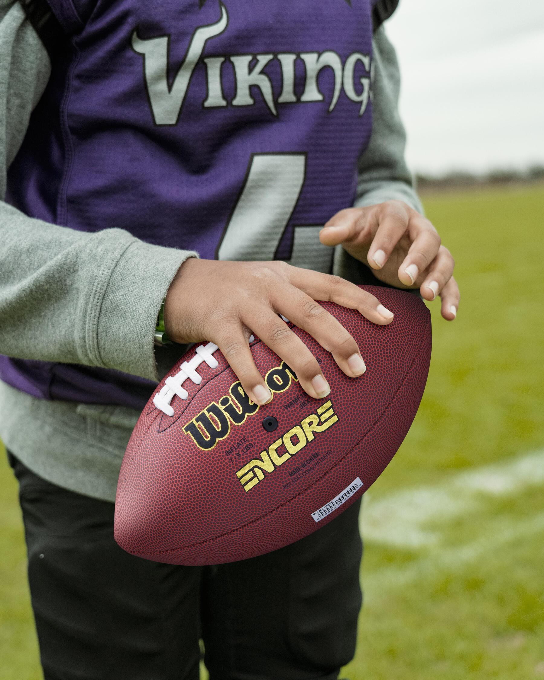 Mann hält einen American Football in der Hand.