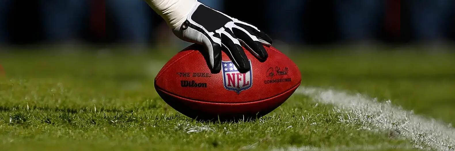 Handschuh an einem American Football auf einer Wiese