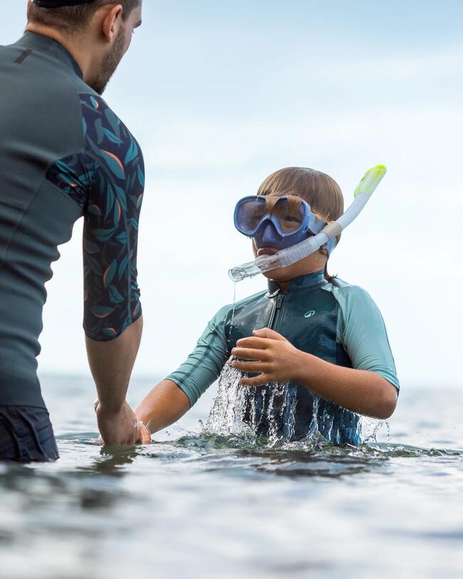 Mann hält Hand von Kind im Wasser, Kind gerade aufgetaucht, Schnorchelmaske und Schnorchel mit Dry Top im Gesicht, Neopren Oberteil