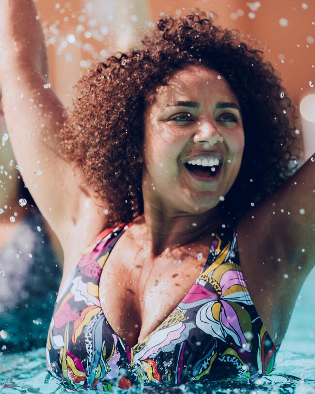 Frau im Pool lacht, Wasser spritzt umher