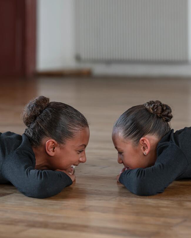 Zwei Mädchen in Ballettkleidung liegen auf dem Boden.