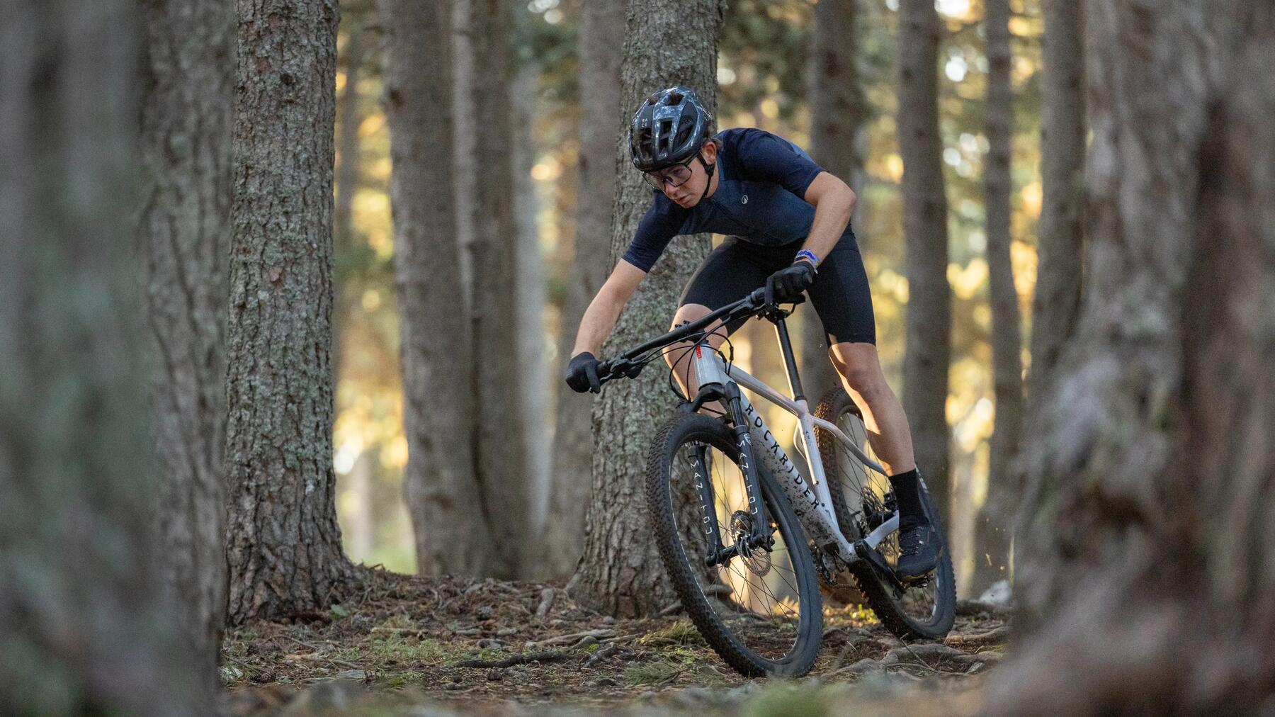 Chłopak w kasku i w okularach jadący rowerem mtb po lesie