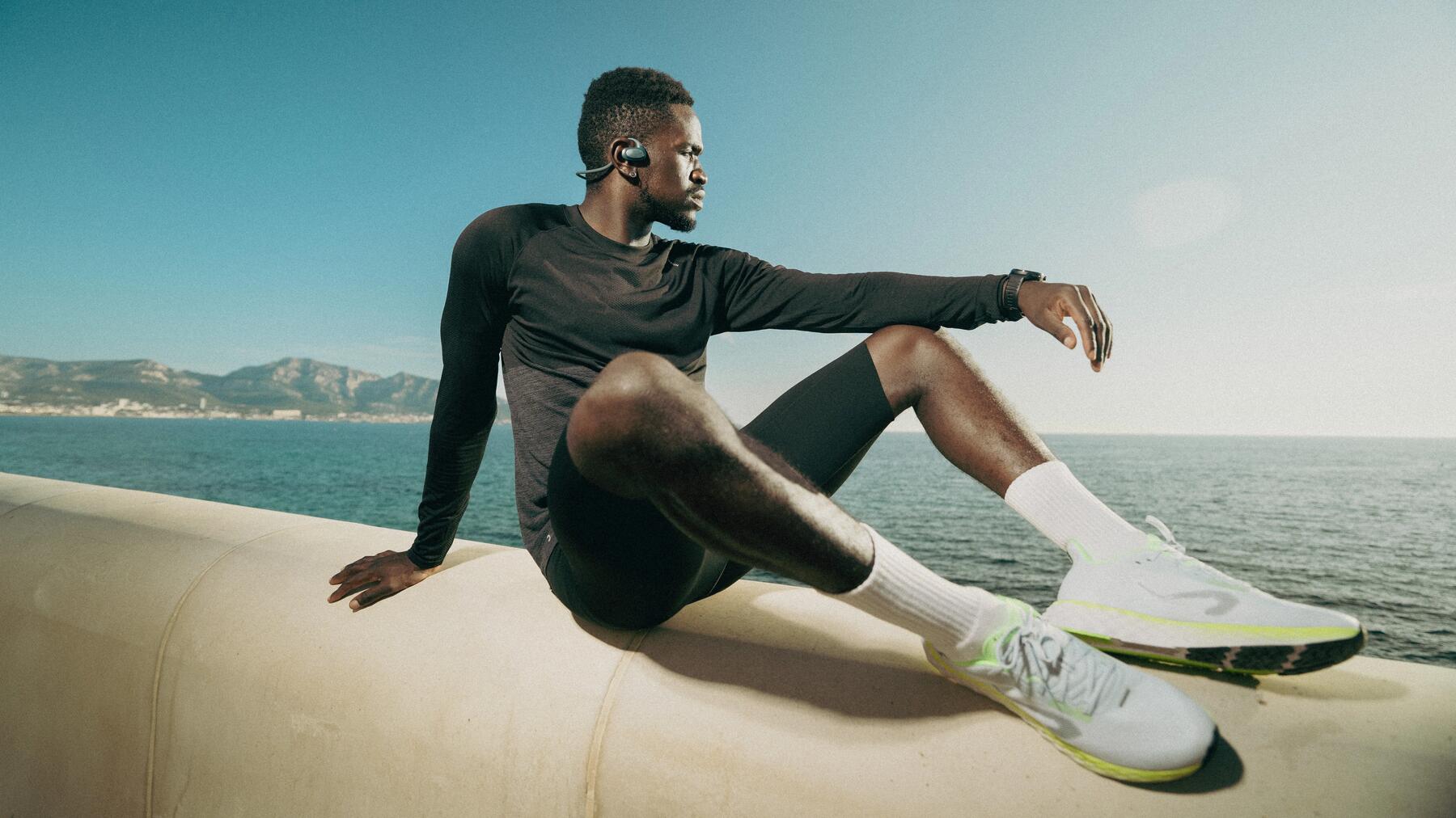 Ein Mann sitzt am Wasser und hat sich nach dem Sport gedehnt
