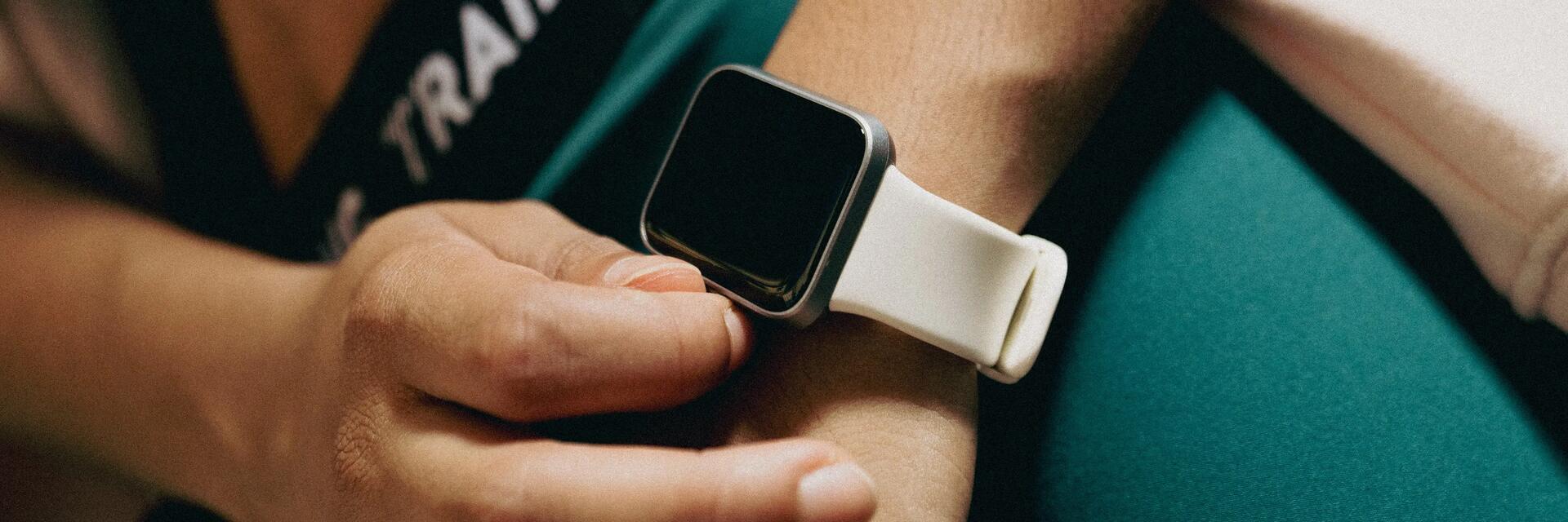 Kobieta w odzieży na siłownię naciskająca przycisk na smartwatchu na ręku